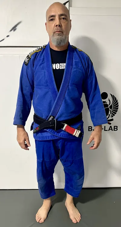 Rodrigo Felizola, cinturón negro segundo dan, de cuerpo entero con el gi azul y el cinturón de BJJ-LAB en el tatami de Montalbán